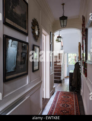 Maison de ville hall d'entrée avec des estampes encadrées et perse rouge runner Banque D'Images