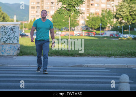 Jeune homme marchant sur zebra crossing Banque D'Images