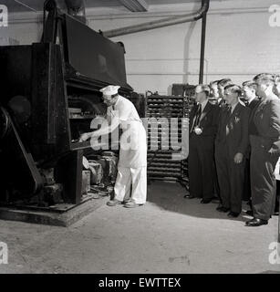 Historique, années 50, male chef de groupe montrant des hommes adultes un grand four à pain de taille industrielle. Banque D'Images