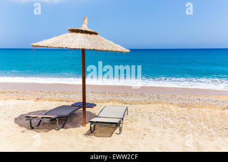 Reed parasol avec deux chaises longues sur la plage près de Blue Sea coast in Greece Banque D'Images