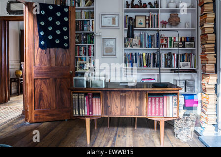 Au milieu du siècle 24 en home office avec un parquet de récupération intégré, des étagères et des livres empilés Banque D'Images