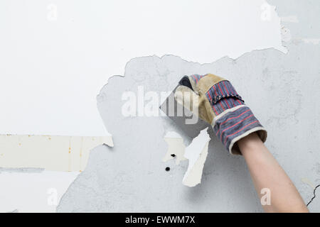 Personne éraflant peinture blanche de mur en béton lors d'un projet de remodelage de la maison Banque D'Images