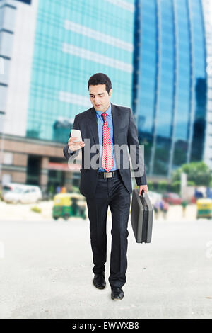 1 Indian Business Man Walking Dialing Cell Phone Banque D'Images