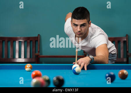 Les jeunes hommes doublure pour frapper la boule sur une table de billard Banque D'Images