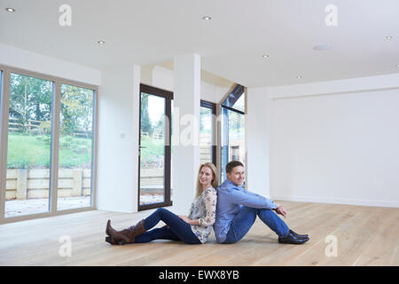 Happy Young Couple Sitting on Floor In New Home Banque D'Images