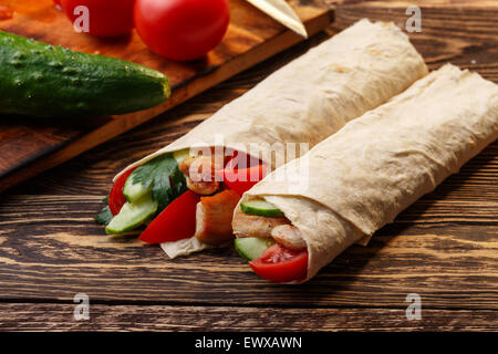 Wrap shawarma traditionnel avec du poulet et des légumes près de ses ingrédients Banque D'Images