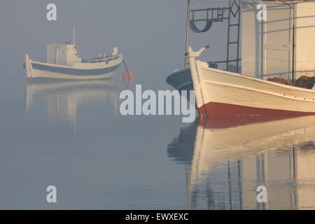 Vue d'un bateau de pêche en bois stern post (premier plan) et un bateau dans le cyan fond brumeux. Diapori bay, Limnos, Grèce Banque D'Images