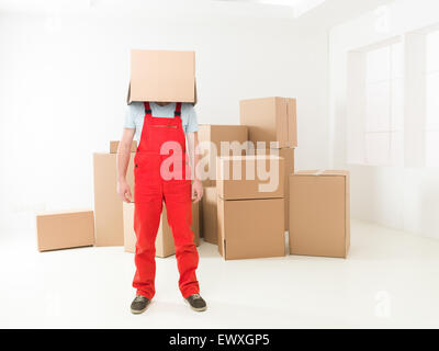 Vue avant du livreur debout dans nouvelle maison avec fort couvrant sa tête. copie espace disponible Banque D'Images