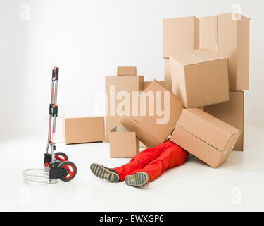 Delivery man laying on plancher couvert dans des boîtes de carton Banque D'Images