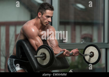L'homme musclé faisant Poids lourd l'exercice pour les biceps Banque D'Images