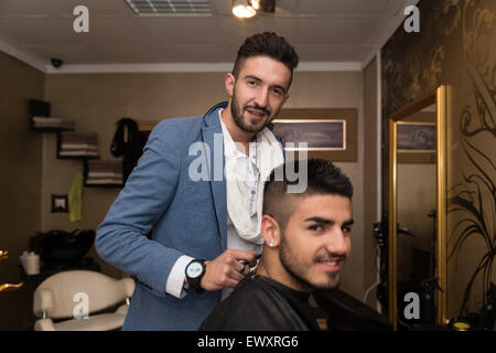 Beau jeune coiffure donnant une nouvelle coupe pour homme Client à Parlour Banque D'Images