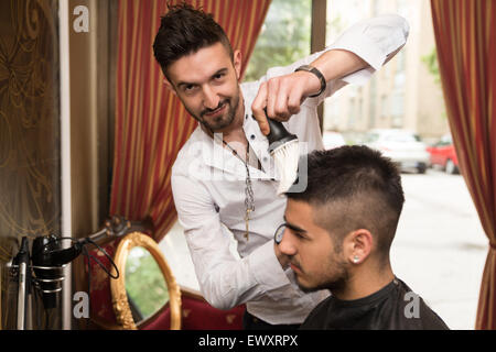 Beau jeune coiffure donnant une nouvelle coupe pour homme Client à Parlour Banque D'Images