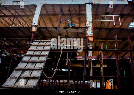 Dhaka, Bangladesh. 2 juillet, 2015. 2 juillet 2015 - Dhaka, Bangladesh - un garçon est assis sur un navire qui est en construction au chantier naval de Dhaka. Travail Travailleurs ici sans minimum de protection de sécurité. Les conditions sont petites et souvent dangereuses, tous les âges travaillent ensemble, et les enfants grandissent dans un monde de dur travail, de l'absent dehors sur l'éducation formelle. © Mohammad Ponir Hossain/ZUMA/ZUMAPRESS.com/Alamy fil Live News Banque D'Images