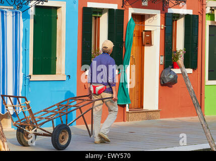 L'homme tirant un chariot le long d'une rue Burano Lagune de Venise Vénétie Italie Europe Banque D'Images