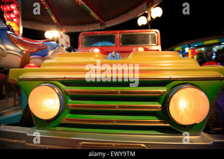 En forme de voiture en plastique coloré s'asseoir à l'échelle locale lunapark carrousel. Myrina, île de Lemnos, Grèce Banque D'Images