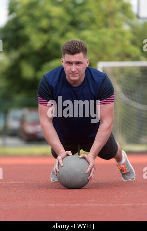 Jeune homme à l'extérieur faisant des pompes sans le ballon d'exercice de musculation Banque D'Images