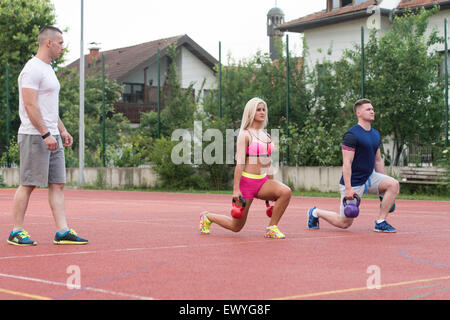 Groupe de jeunes gens faisant une électrique avec moniteur extérieur Exercice Bell Banque D'Images