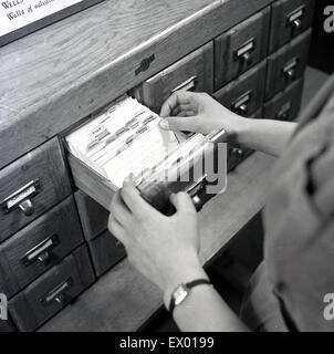 Historique, 1950, photo montre un indice de la carte en cours d'ouverture du bac par une femme bibliothécaire. Le système de la carte d'index est un manuel, l'enregistrement sur support papier, utilisé dans de nombreux domaines de l'administration et de l'entreprise à la fois pour l'enregistrement et le stockage de données ou d'informations, généralement sur une base alphabétique. Banque D'Images