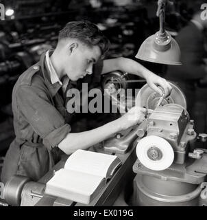 Historique, 1950, les jeunes apprentis d'ingénierie avec reference book, travaillant à un tour. Banque D'Images