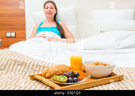 Petit-déjeuner au lit d'une chambre d'hôtel d'une belle brune Banque D'Images