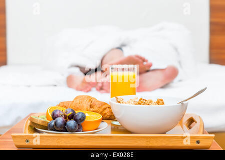 Des couples pieds luxuriate dans lit et d'un plateau de nourriture Banque D'Images