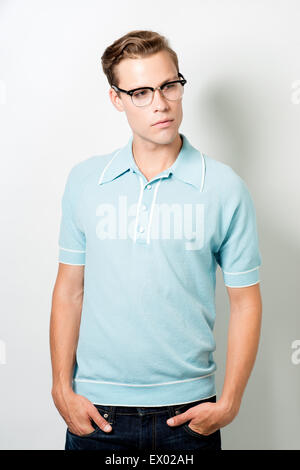 Un beau jeune homme portant des lunettes et 50s vintage top, posant avec les mains en poche, à l'écart Banque D'Images