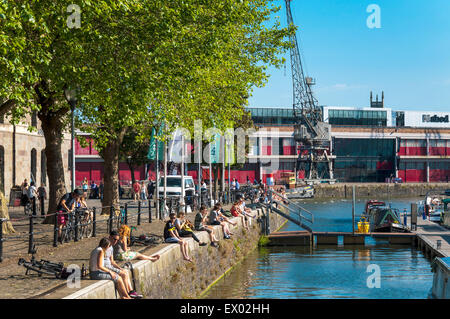 Des gens assis sur la vérification à quai à St Augustine's Reach dans le port de Bristol, Bristol, Angleterre. Banque D'Images