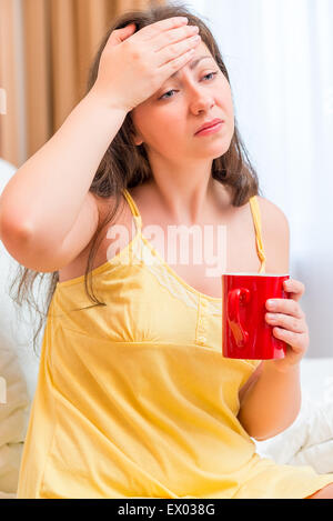 Sick girl dans le lit avec une tasse de thé Banque D'Images