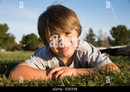 Portrait of smiling boy lying on grass park Banque D'Images