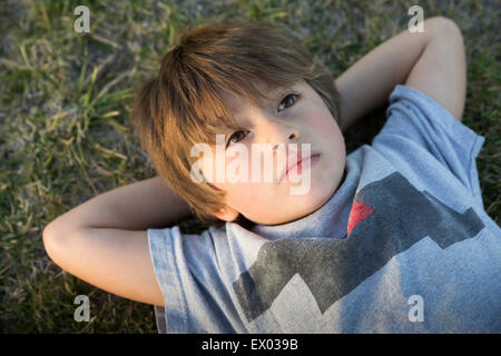 Portrait of boy lying on grass parc regardant Banque D'Images