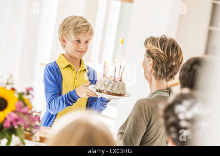 Boy handing grand-mère cake party dans la salle à manger Banque D'Images