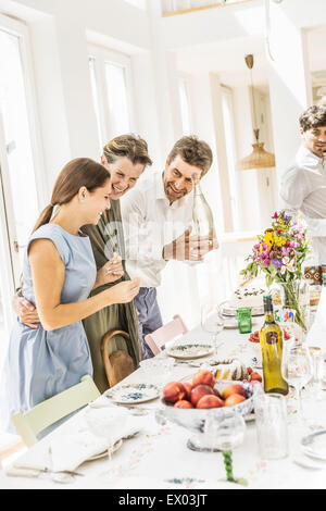 Couple et sa fille adulte la préparation de table de salle à manger pour partie Banque D'Images