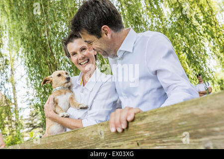 Portrait de couple avec chien de compagnie, standing by fence in forest Banque D'Images