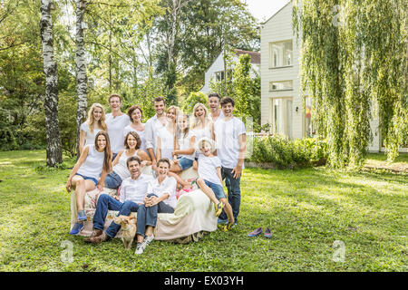 Portrait de groupe de gens assis sur et autour d'un canapé, en face de country house Banque D'Images