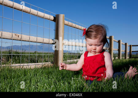 Portrait of cute young woman sitting on grass Banque D'Images