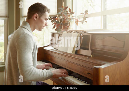 Jeune homme jouant du piano dans la salle de séjour Banque D'Images