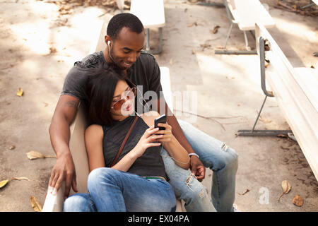 Jeune couple assis ensemble, partageant les écouteurs Banque D'Images