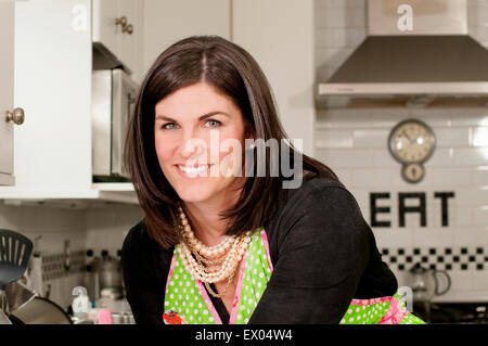 Mid adult woman wearing apron dans la cuisine, portrait Banque D'Images