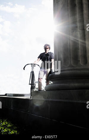 Bike messenger en tenant la colonne à côté de pause Banque D'Images