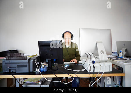 Man in creative studio portant des écouteurs Banque D'Images