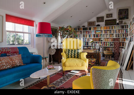 Fauteuil à ailes jaunes, Julep président et bold blue canapé dans salon avec kilim ouzbek, les arts autochtones et un livre qu'elle Banque D'Images