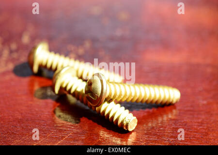 Trois vis en laiton sur le dessus d'une table en bois Banque D'Images