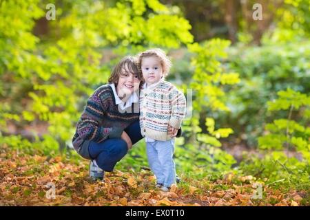 Adorable petite fille et son frère l'âge de l'adolescence à jouer ensemble dans un magnifique parc ensoleillée d'automne Banque D'Images