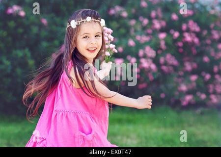 Bébé Adorable petite fille s'amuser à l'extérieur et la danse, tourbillonnant autour, holding roses, portant robe rose Banque D'Images