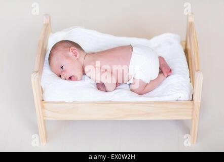 Adorable petit bébé nouveau-né dans un lit en bois Banque D'Images