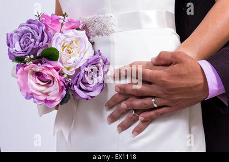 Les jeunes mariés à l'aide de mariage et un bouquet de roses Banque D'Images