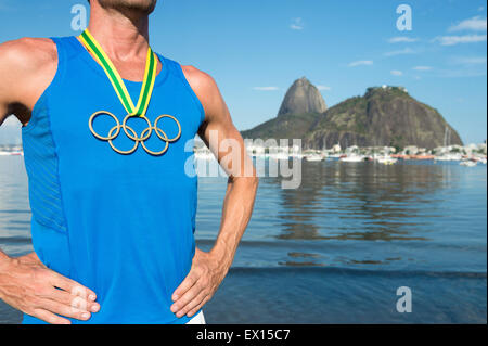 RIO DE JANEIRO, Brésil - Mars 05, 2015 : athlète signifie porter anneaux olympiques médaille d'or en face de Sugarloaf Mountain skyline. Banque D'Images