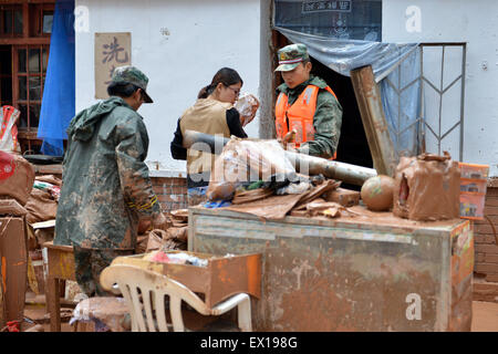 Sunan, Province de Gansu en Chine. 4 juillet, 2015. Les matériaux de transfert de policiers armés pour les résidents dans le comté de Sunan, nord-ouest de la Chine, la province du Gansu, le 4 juillet 2015. Une forte pluie a provoqué un glissement de Sunan, endommageant le samedi 63 maisons. Credit : Wu Xuefeng/Xinhua/Alamy Live News Banque D'Images