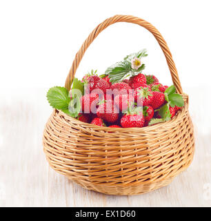 Fraises fraîches dans le panier sur une table en bois isolé sur blanc Banque D'Images