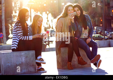 Un groupe d'amis s'amusant avec les smartphones dans la rue Banque D'Images